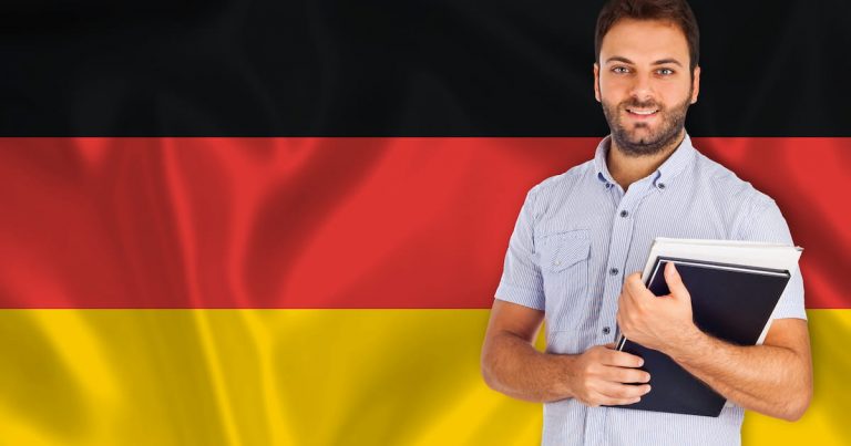Man Standing In Front Of The German Flag With A Book In Hand.