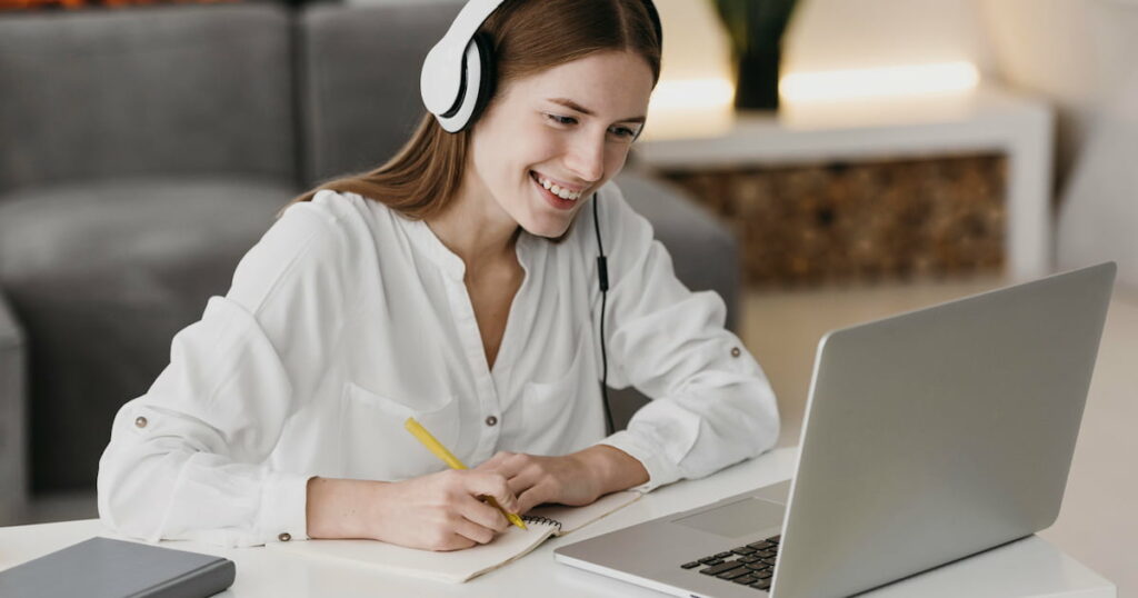 Young woman smiling at laptop during an online English course