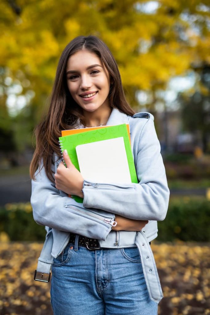 A Student Holding Notebooks And Smiling